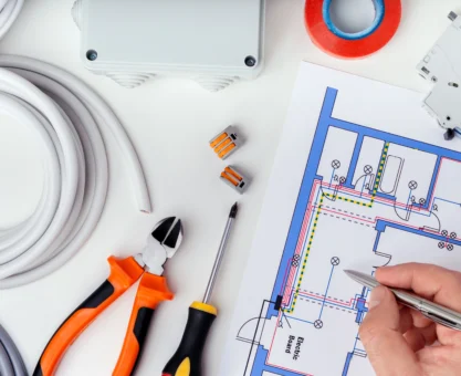 Ferramentas de elétrica e um projeto elétrico de instalação detalhado numa mesa de trabalho, conforme normas abnt.