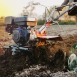 Imagem de uma pessoa utilizando uma máquina agrícola para preparo do solo, ideal para ilustrar o funcionamento de soft starter em equipamentos industriais.