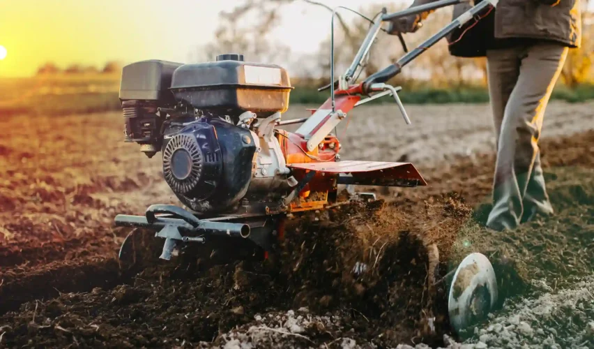 Imagem de uma pessoa utilizando uma máquina agrícola para preparo do solo, ideal para ilustrar o funcionamento de soft starter em equipamentos industriais.