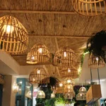 Elegantes lustres pendentes de fibra natural decorando o teto de um ambiente interno aconchegante, com iluminação suave e plantas decorativas ao redor.