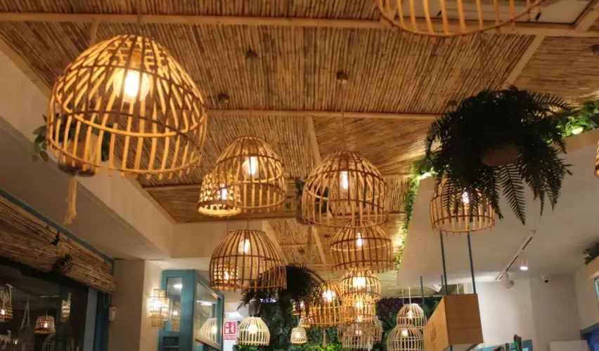 Elegantes lustres pendentes de fibra natural decorando o teto de um ambiente interno aconchegante, com iluminação suave e plantas decorativas ao redor.