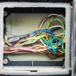 Fios elétricos coloridos dentro de caixa de passagem elétrica com isolamento e emaranhado