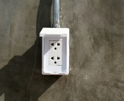 Imagem de tomada de sobrepor instalada em uma parede cinza para ilustrar o artigo da EletroNunes sobre o assunto.