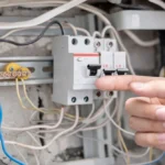 Disjuntor desarmando em painel elétrico, ação frequente em manutenção e segurança elétrica, com um dedo indicando o aparelho, mostrando funcionamento ou emergência elétrica.