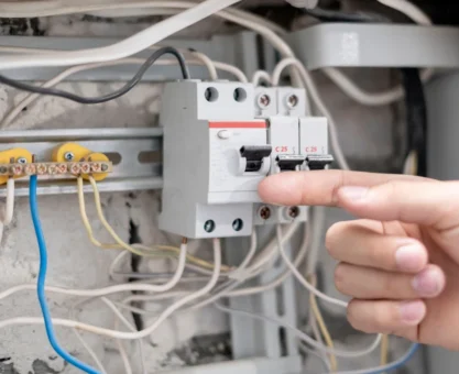 Disjuntor desarmando em painel elétrico, ação frequente em manutenção e segurança elétrica, com um dedo indicando o aparelho, mostrando funcionamento ou emergência elétrica.