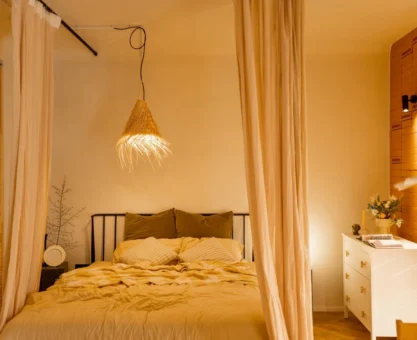 Iluminação no quarto com luminária pendente estilo cúpula de tecido sobre a cama, luz quente e cortinas claras, criando ambiente aconchegante e moderno.