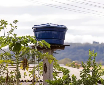 tanque fortlev instalado em área rural, com reservatório azul sobre base de concreto, cercado por plantas e vista para montanhas ao fundo