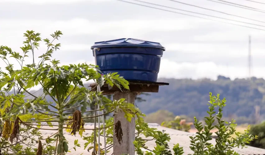 tanque fortlev instalado em área rural, com reservatório azul sobre base de concreto, cercado por plantas e vista para montanhas ao fundo